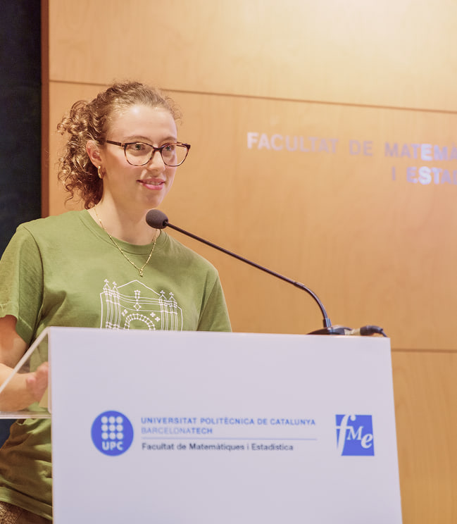 Una organitzadora presentant des de l'atril de la Facultat de Matemàtiques i Estadística